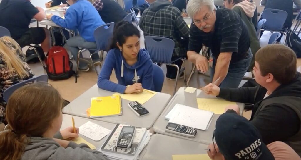 Students working around a table with a teacher